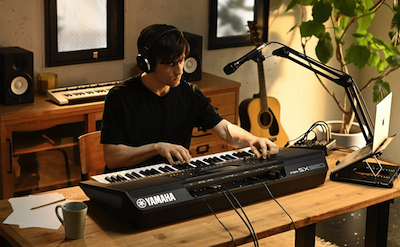 Photo of a person playing the Yamaha Arranger Workstation PSR-SX920 in a room with headphones on.